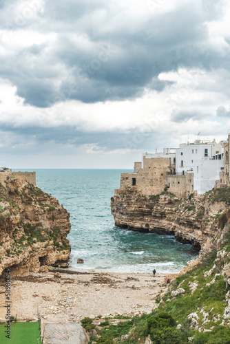 Polignano a Mare, Bari, Italy. Old town built on the rocky cliffs. Traveling concept background with old traditional houses, dramatic cloudy sky and beautiful view of Mediterranean Sea, vertical