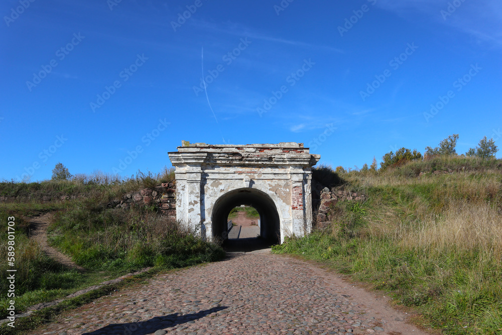 Fototapeta premium Stone roadway and old gate near the city of Vyborg, Russia. Bright autumn landscapes of popular tourist destination and landmark.