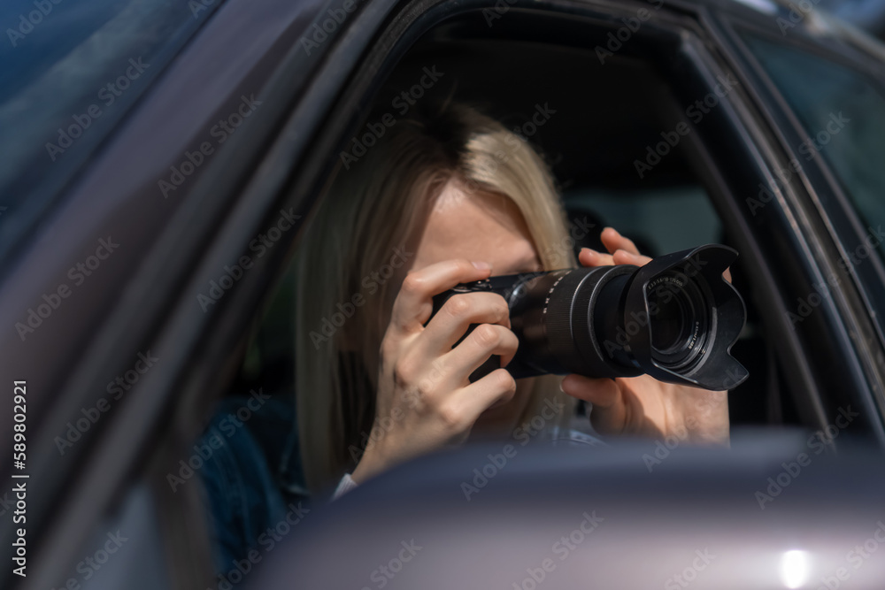 Young blonde woman takes pictures sitting in a car. Concept of journalism, detective, papparation Young blonde woman takes pictures sitting in a car. Concept of journalism, detective, papparation