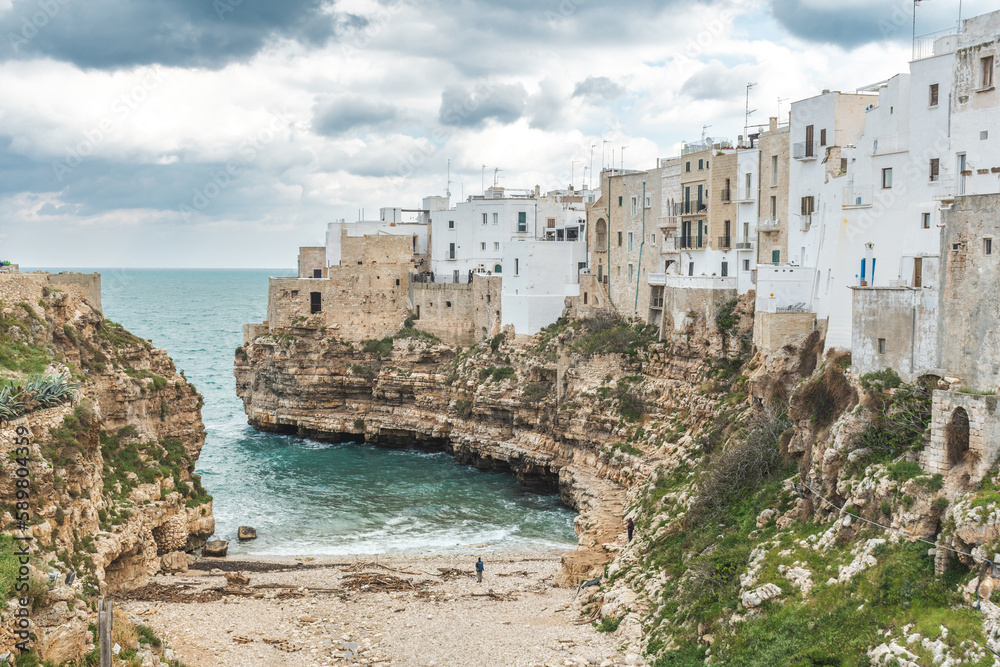 Polignano a Mare, Bari, Italy. Old town built on the rocky cliffs. Traveling concept background with old traditional houses, dramatic cloudy sky and beautiful view of Mediterranean Sea