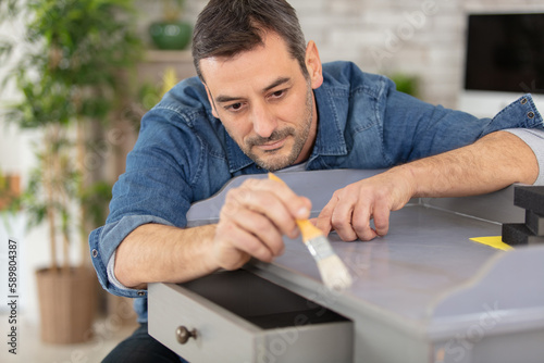 young man varnishig cabinet at home