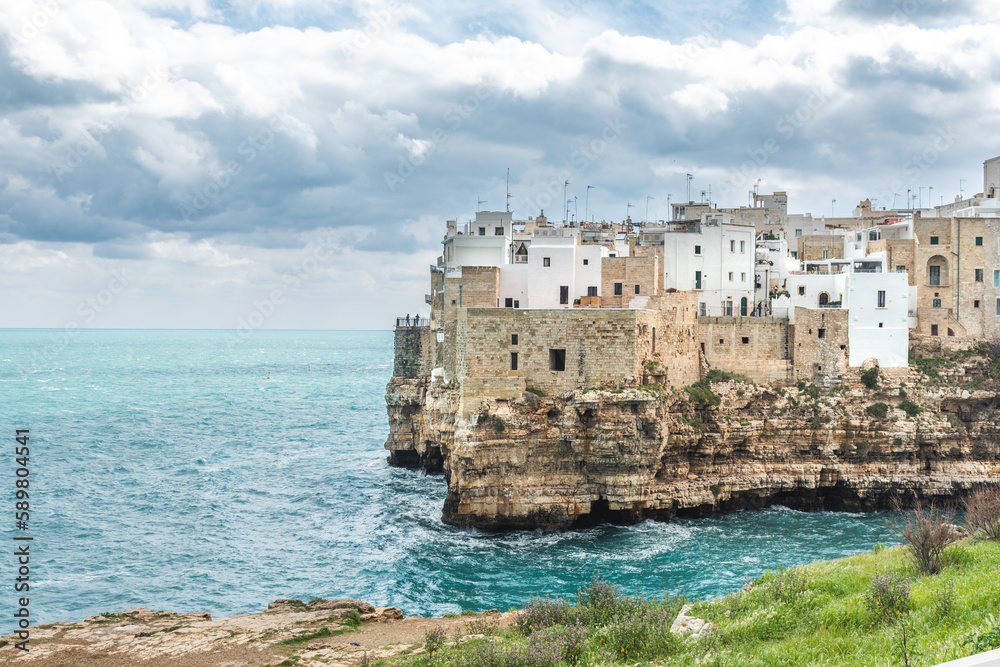 Polignano a Mare, Bari, Italy. Old town built on the rocky cliffs. Traveling concept background with old traditional houses, dramatic cloudy sky and beautiful view of Mediterranean Sea Polignano a Mare, Bari, Italy. Old town built on the rocky cliffs. Traveling concept background with old traditional houses, dramatic cloudy sky and beautiful view of Mediterranean Sea