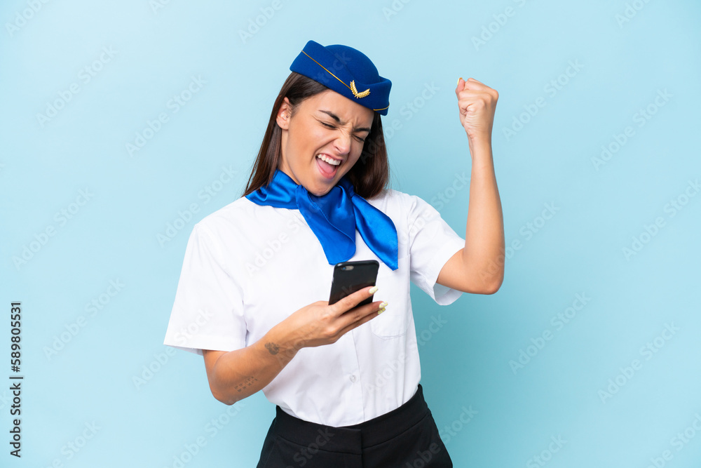 Airplane stewardess caucasian woman isolated on blue background with phone in victory position Airplane stewardess caucasian woman isolated on blue background with phone in victory position