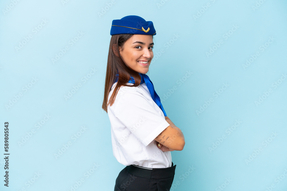 Airplane stewardess caucasian woman isolated on blue background with arms crossed and looking forward Airplane stewardess caucasian woman isolated on blue background with arms crossed and looking forward