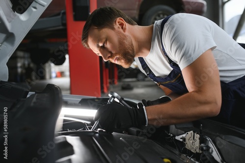 Auto mechanic working on car engine in mechanics garage. Repair service. © Serhii