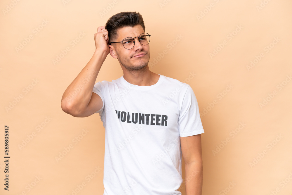 Young volunteer caucasian man isolated on beige background having doubts and with confuse face expression Young volunteer caucasian man isolated on beige background having doubts and with confuse face expression