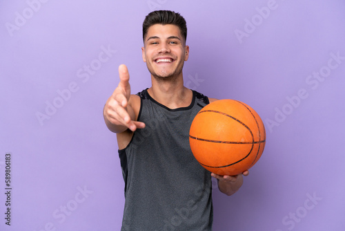 young caucasian woman  basketball player man isolated on purple background shaking hands for closing a good deal © luismolinero