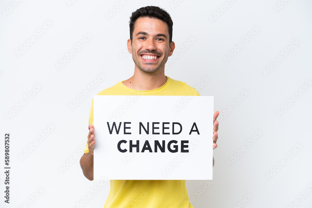 Young handsome man over isolated white background holding a placard with text We Need a Change with happy expression Young handsome man over isolated white background holding a placard with text We Need a Change with happy expression