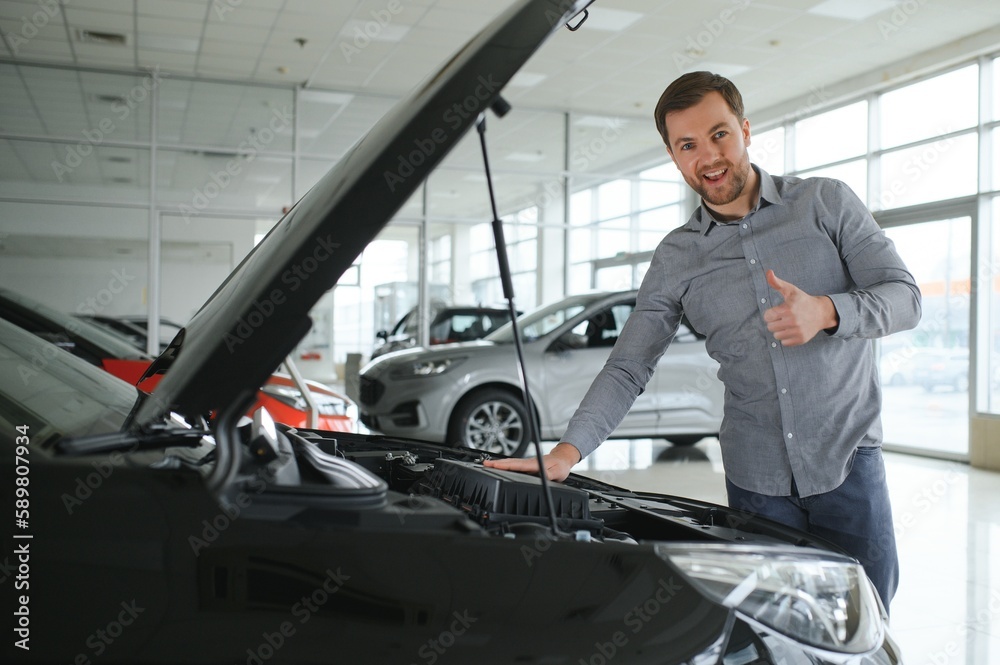 Young man is choosing a new vehicle in car dealership. Young man is choosing a new vehicle in car dealership.