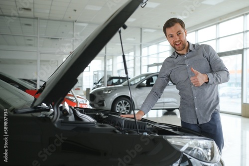 Young man is choosing a new vehicle in car dealership.