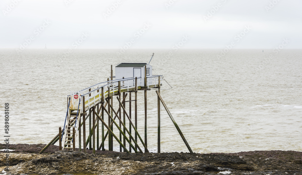 Fisherman's hut made of wood and resting on piles along the Atlantic ocean's coastline during a cloudy day Fisherman's hut made of wood and resting on piles along the Atlantic ocean's coastline during a cloudy day