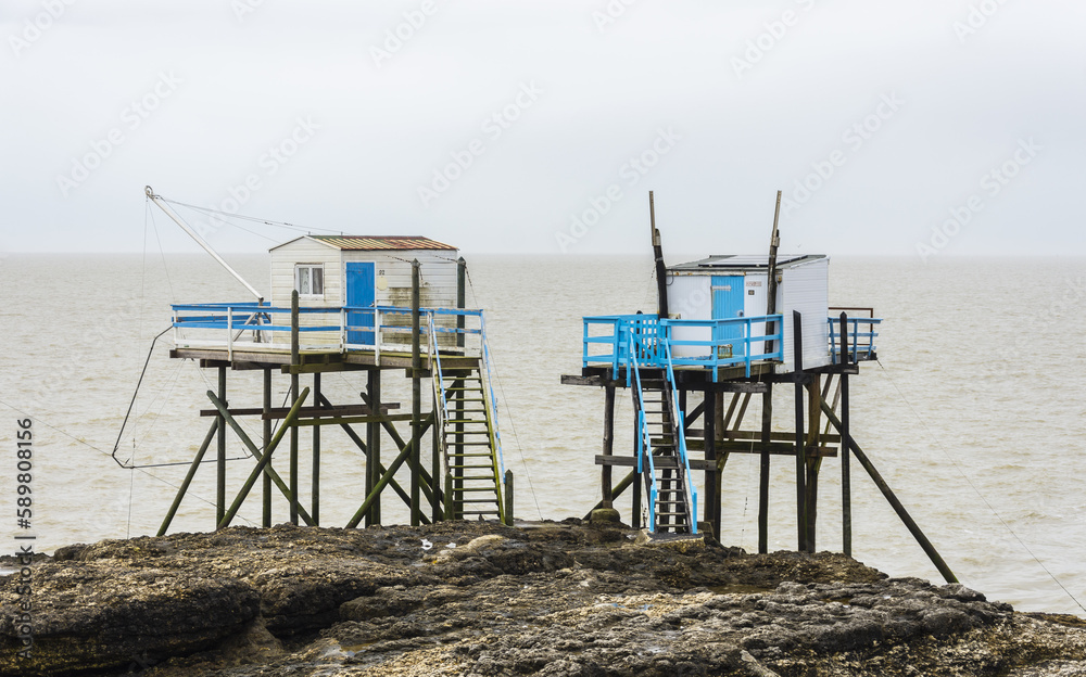Fishermen's hut made of wood and resting on piles along the Atlantic ocean's coastline during a cloudy day