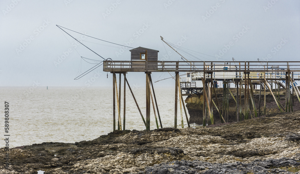Fishermen's hut made of wood and resting on piles along the Atlantic ocean's coastline during a cloudy day