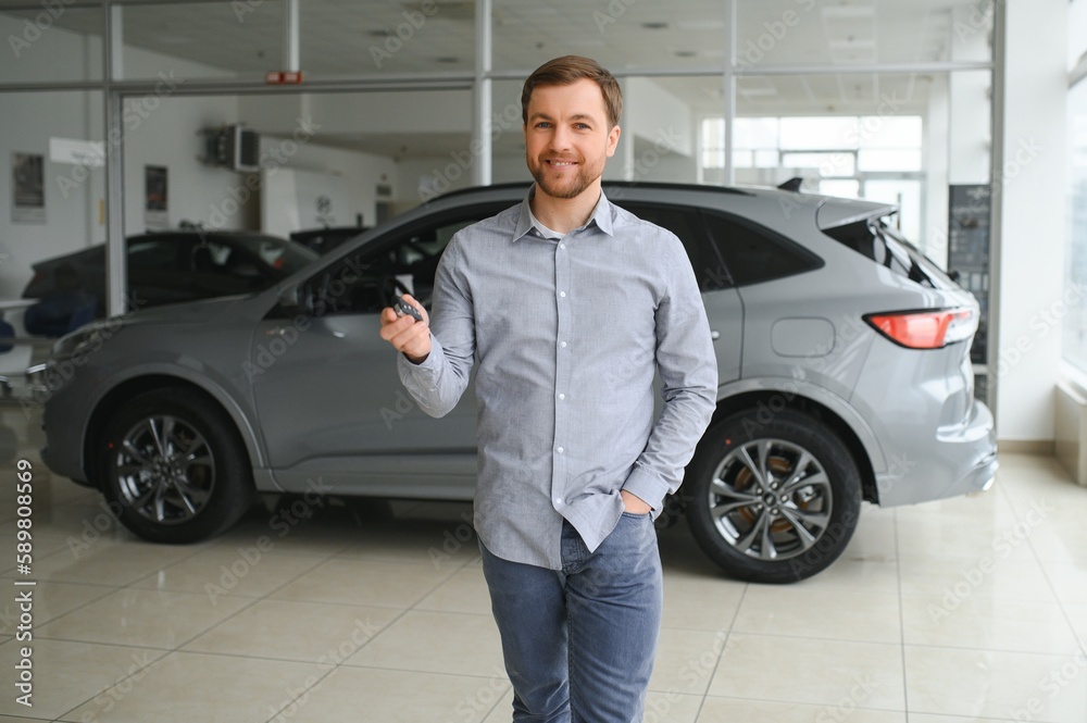 Yes, that's my new car. Customer in car dealership. Young man with keys in hand. Yes, that's my new car. Customer in car dealership. Young man with keys in hand.