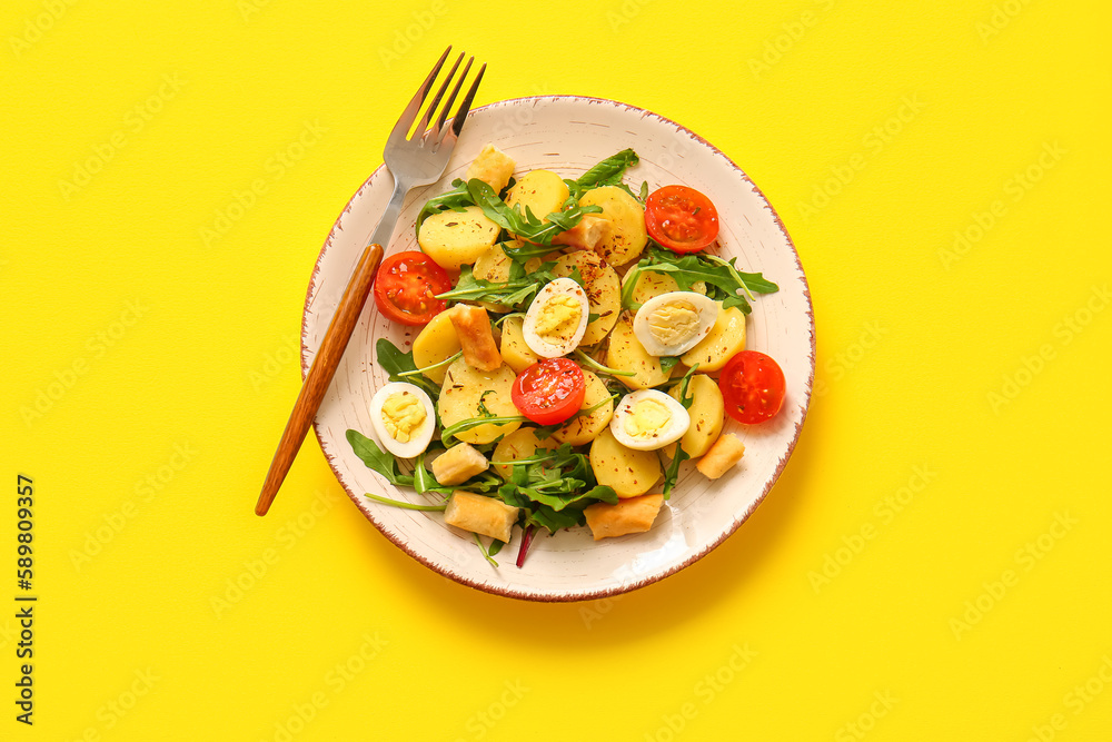 Plate of tasty potato salad with eggs and tomatoes on yellow background, top view