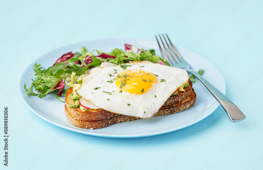 Delicious sandwich with fried egg and salad on blue background