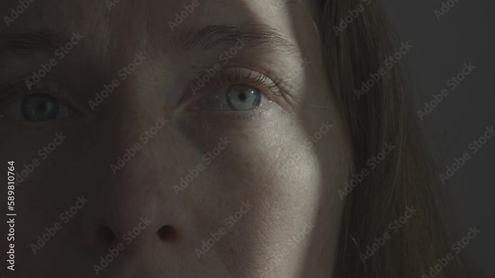 Portrait of a woman with a streak of sunlight across her eye and cheek. Psychology and psychiatry. Fear of the environment