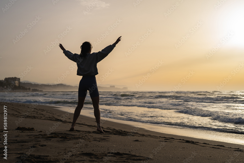 beautiful young girl is engaged in fitness on the seashore at dawn
