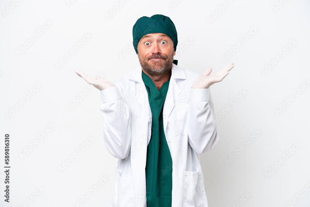 Middle age surgeon in green uniform isolated on white background having doubts while raising hands