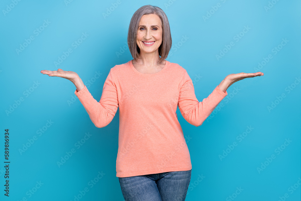 Portrait of optimistic friendly senior person with bob hairdo wear pink shirt arms comparing products isolated on blue color background Portrait of optimistic friendly senior person with bob hairdo wear pink shirt arms comparing products isolated on blue color background