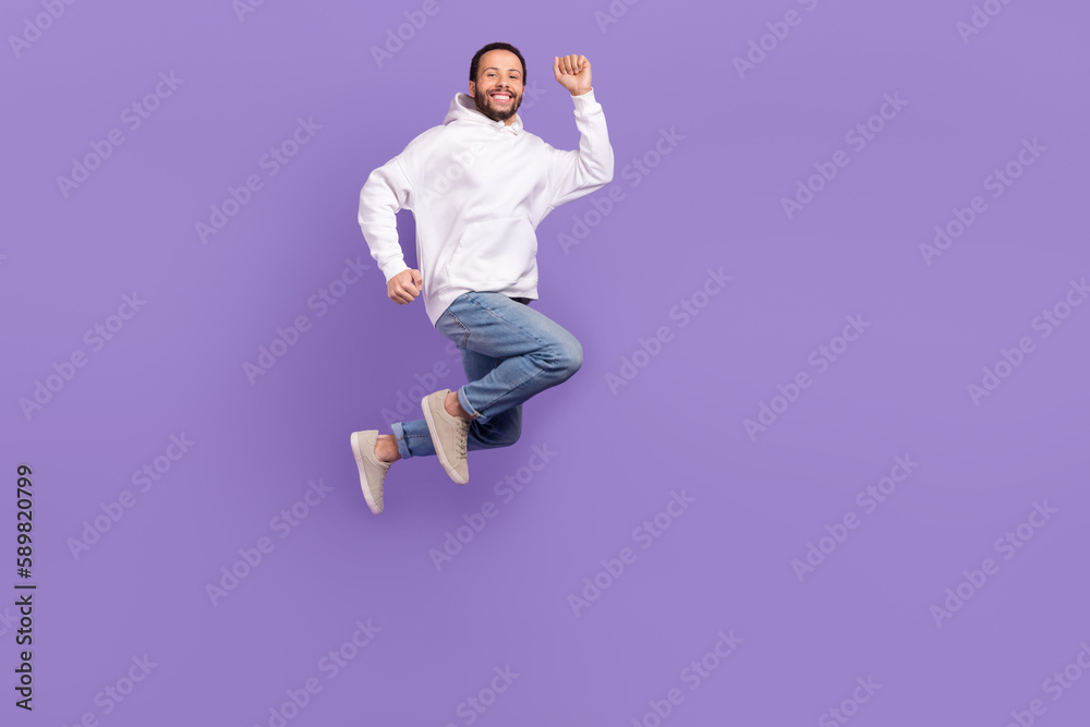 Full body picture of young overjoyed man running jumping feel his high speed promo new hoodie advert isolated on purple color background Full body picture of young overjoyed man running jumping feel his high speed promo new hoodie advert isolated on purple color background