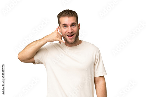 Young handsome caucasian man isolated on green chroma background making phone gesture. Call me back sign