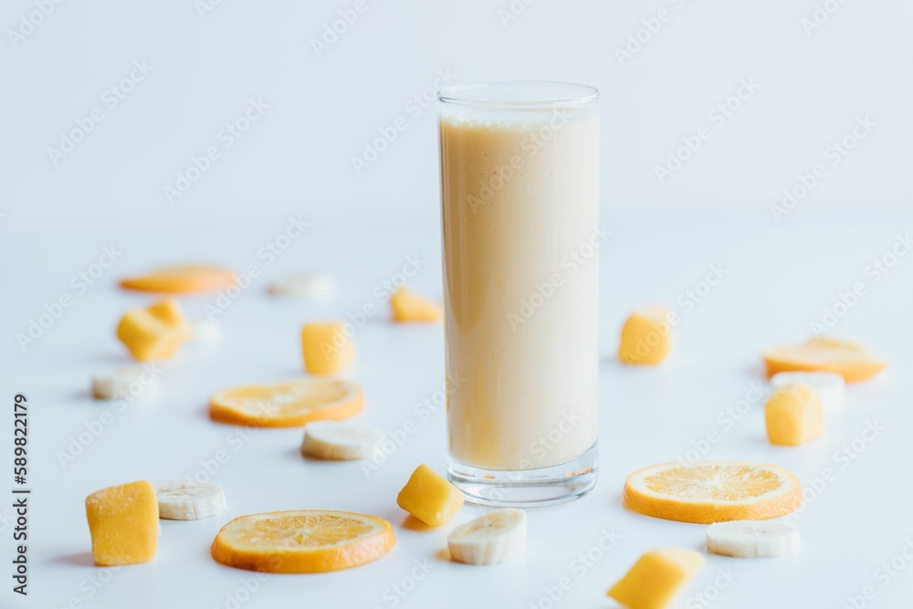 Closeup shot of a glass of milkshake with oranges on a white background Closeup shot of a glass of milkshake with oranges on a white background