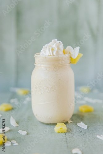 Vertical closeup shot of a glass of a milkshake surrounded by fruits