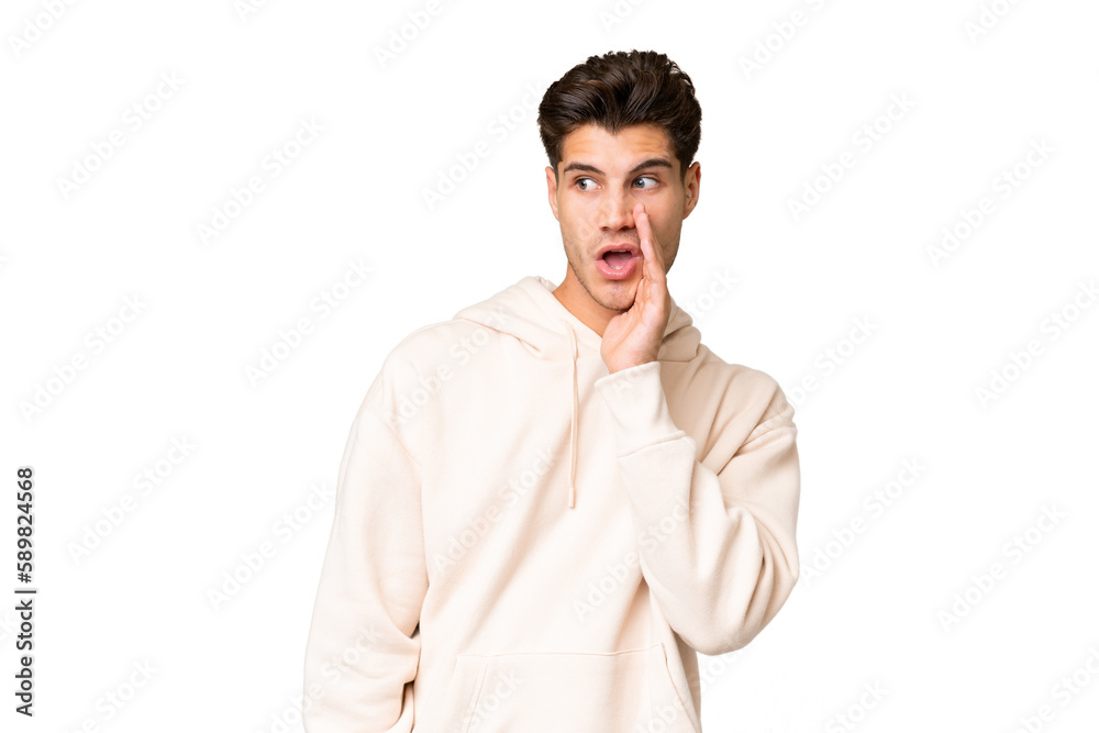 Young caucasian handsome man over isolated background whispering something with surprise gesture while looking to the side