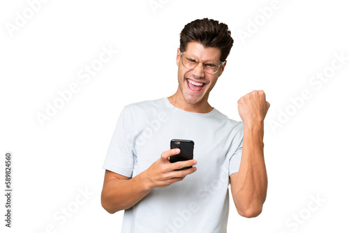 Young caucasian handsome man over isolated background with phone in victory position © luismolinero