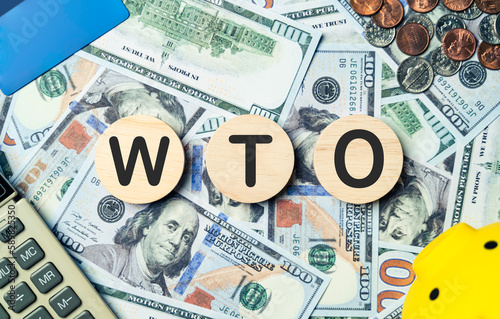 WTO text in wooden circle on Banknotes background, credit card, piggybank, calculator. World Trade Organization, Future planning goals, opportunity, challenge, business strategy and financial concept. photo