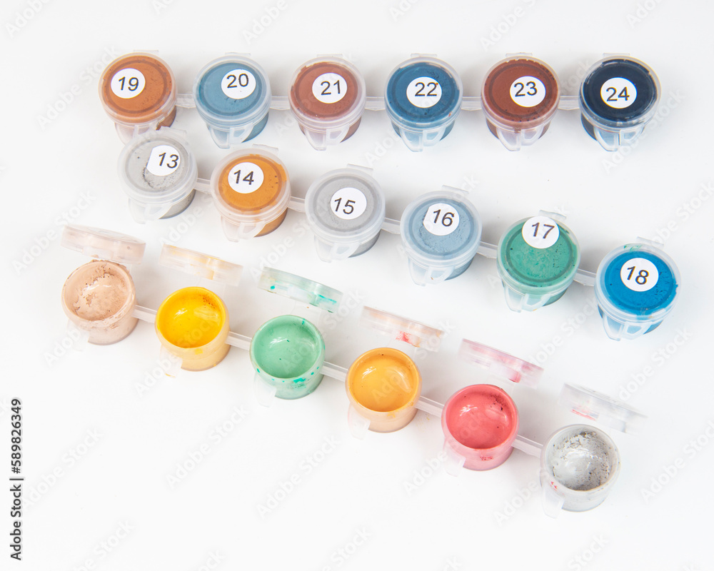 Small jars filled with paint on a painted canvas. Painting by numbers. Bright and colorful. Small jars filled with paint on a painted canvas. Painting by numbers. Bright and colorful.