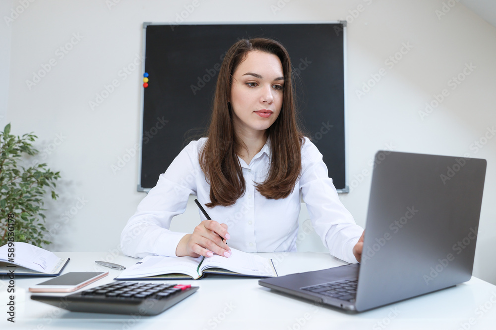 Portrait of a young woman working at her laptop in the office