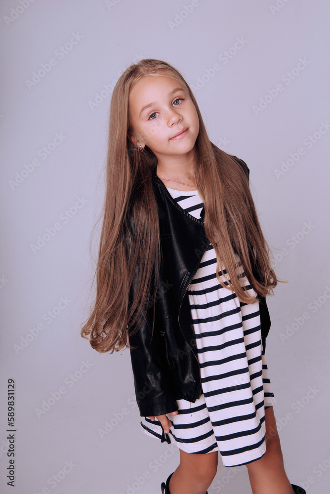 Fototapeta premium Cute happy little blonde girl with long hair wear fashionable clothing 5-7 years old, retouched portrait jumping posing on white
