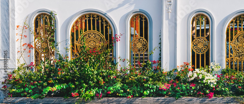 A white building with gold gate red yellow flowers background green luxury splendor