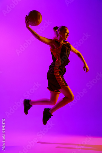 Full-length dynamical image of young female basketball player, girl training with ball against white studio background. Concept of professional sport, hobby, healthy lifestyle, action and motion