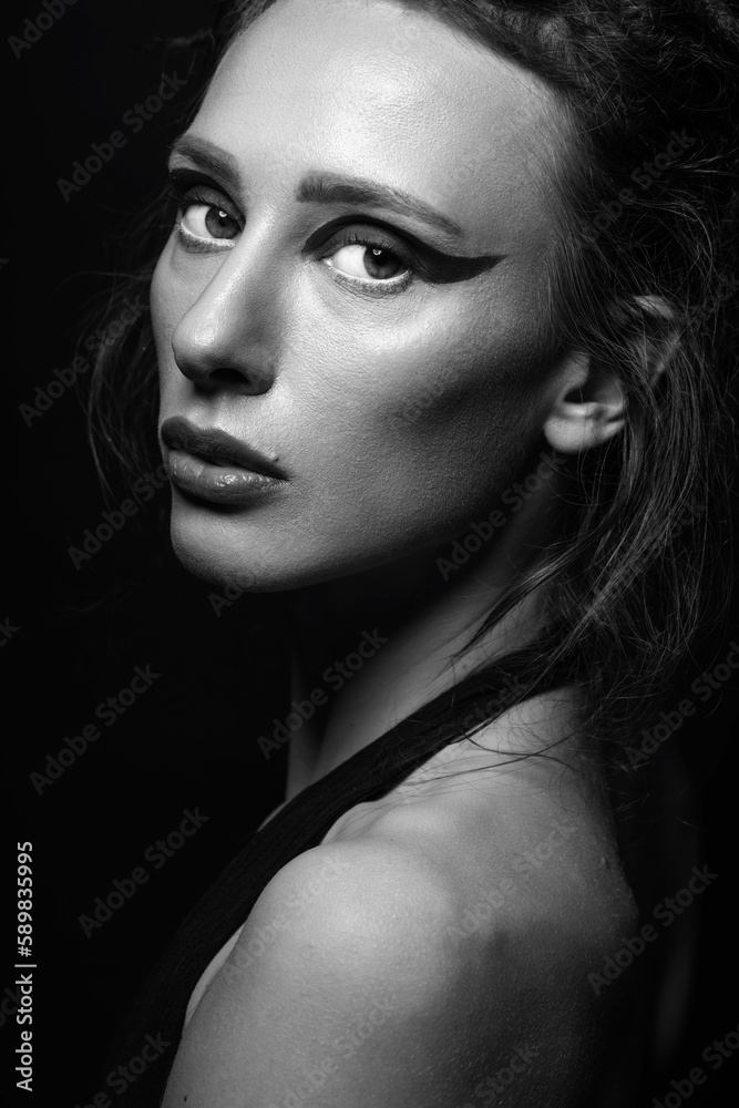 Fashion and make-up concept. Studio portrait of beautiful woman with red shadows, long and dark dreadlocks hair looking at camera with seductive look. Studio shot. Black and white image