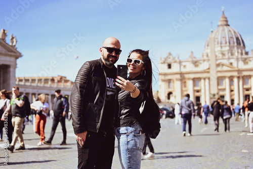 Happy smiling beautiful Tourists couple traveling at Rome, Italy, poses and making photos in front of Vatican City at, Rome, Italy.Concept of Italian gastronomy and travel. Italian couple having