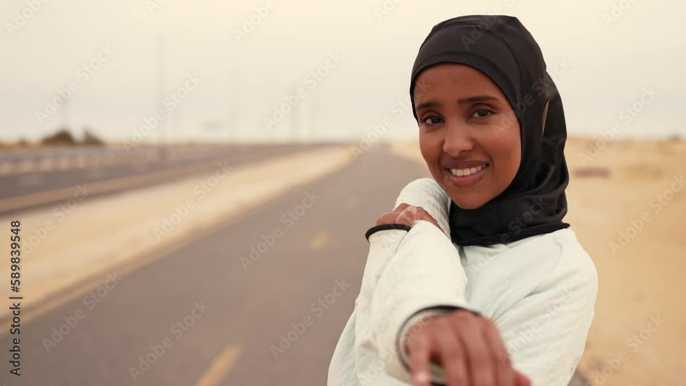 Beautiful female runner wearing sport abaya running in the desert in