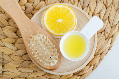 Lemon juice, lemon slice and wooden hairbrush. Ingredients for preparing homemade hair toner or beauty mask. Natural hair care, homemade spa and beauty treatment recipe. Top view