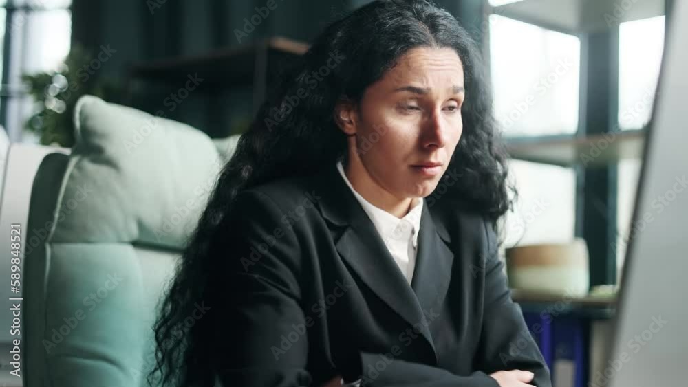 Boring tired young multiethnic businesswoman with lack of motivation and concentration looking at watch waiting for the end of work day sitting at desk in the modern office workplace Procrastination Boring tired young multiethnic businesswoman with lack of motivation and concentration looking at watch waiting for the end of work day sitting at desk in the modern office workplace Procrastination