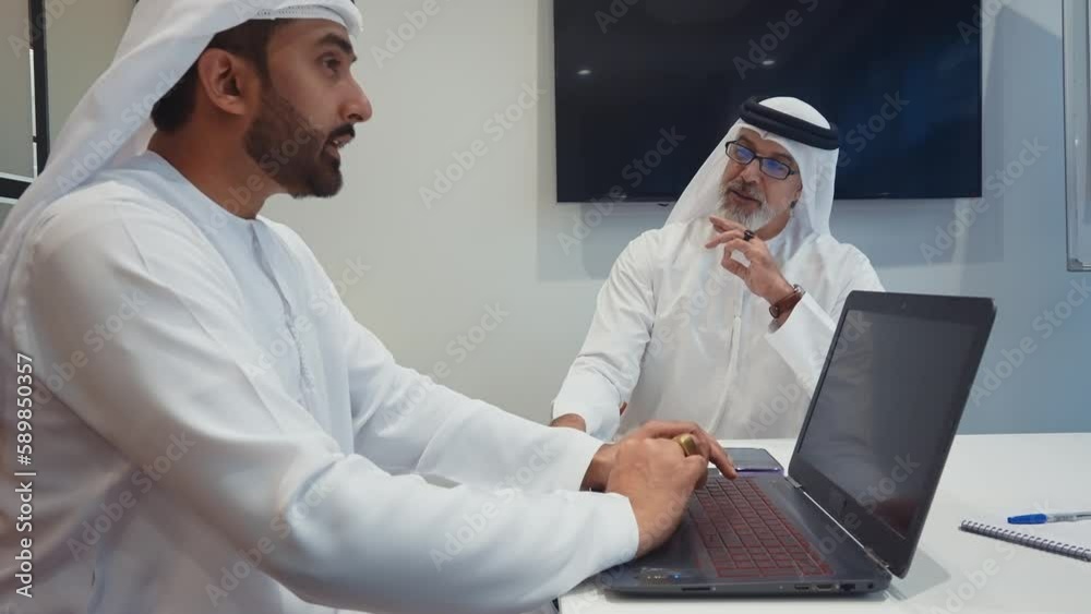 Business team at work in a office in Dubai. Locals from united arab emirates working on a new project wearing the formal traditional white outfit Business team at work in a office in Dubai. Locals from united arab emirates working on a new project wearing the formal traditional white outfit