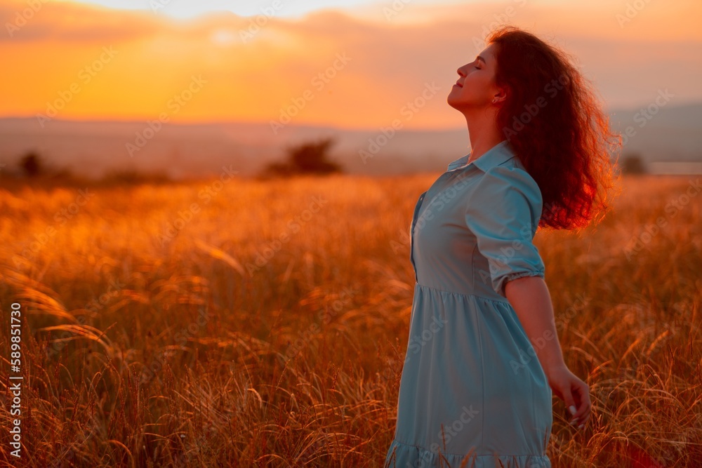 Obraz premium Woman on field wheat with sunset background