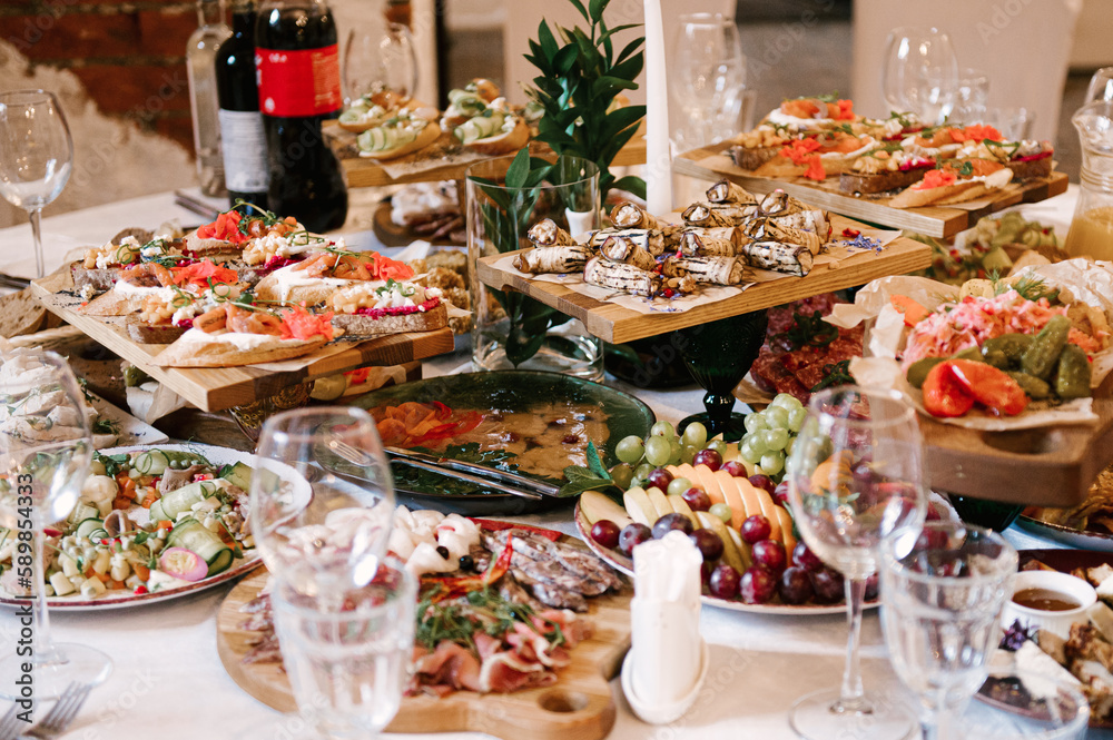 A set of Italian snacks for a buffet. A variety of cheeses, cold cuts bruschetta, pickled cucumbers, tomatoes on a wooden background