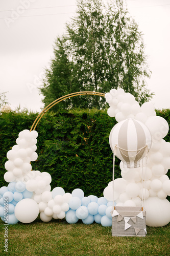 Decorations for holiday party. A lot of balloons blue and white colors. Round photo zone with balls next to a ball with a basket for a child