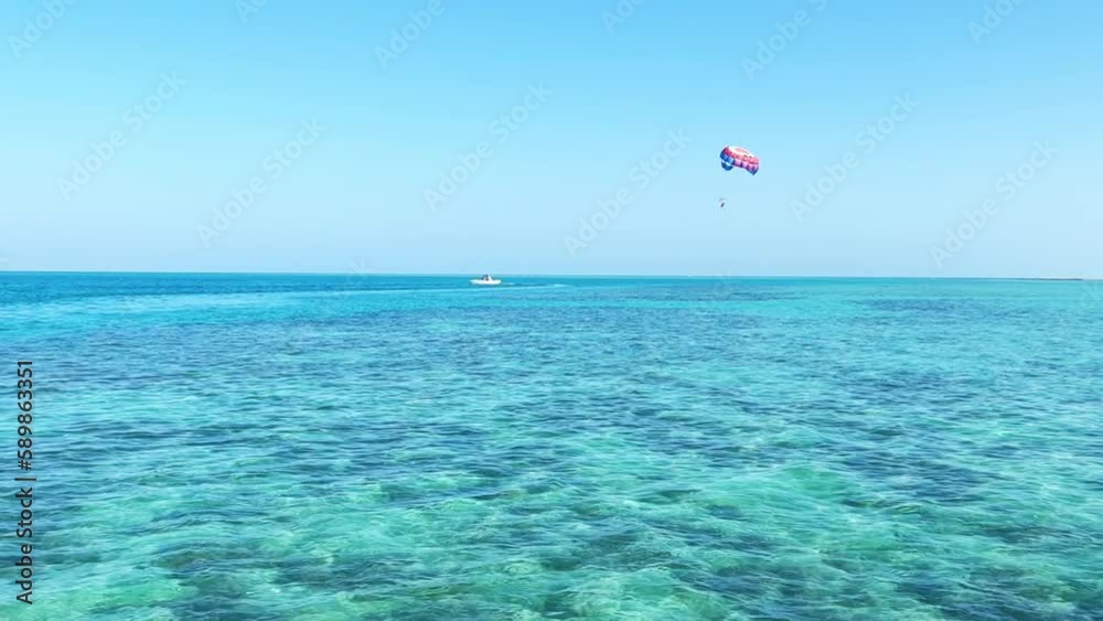 Parachute flight over the Red Sea. Blue water with sun glare and swimming fish in Egypt. The seaside resort has an all-inclusive system. Hurghada 2022 Parachute flight over the Red Sea. Blue water with sun glare and swimming fish in Egypt. The seaside resort has an all-inclusive system. Hurghada 2022