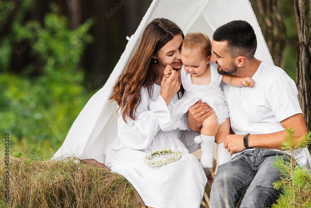 Happy young family spends time together in nature. Young parents hug their little baby daughter. Happy young family spends time together in nature. Young parents hug their little baby daughter.