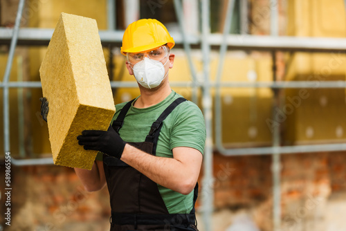 Builder holds mat of mineral wool for insulating buildings. Space for text. photo