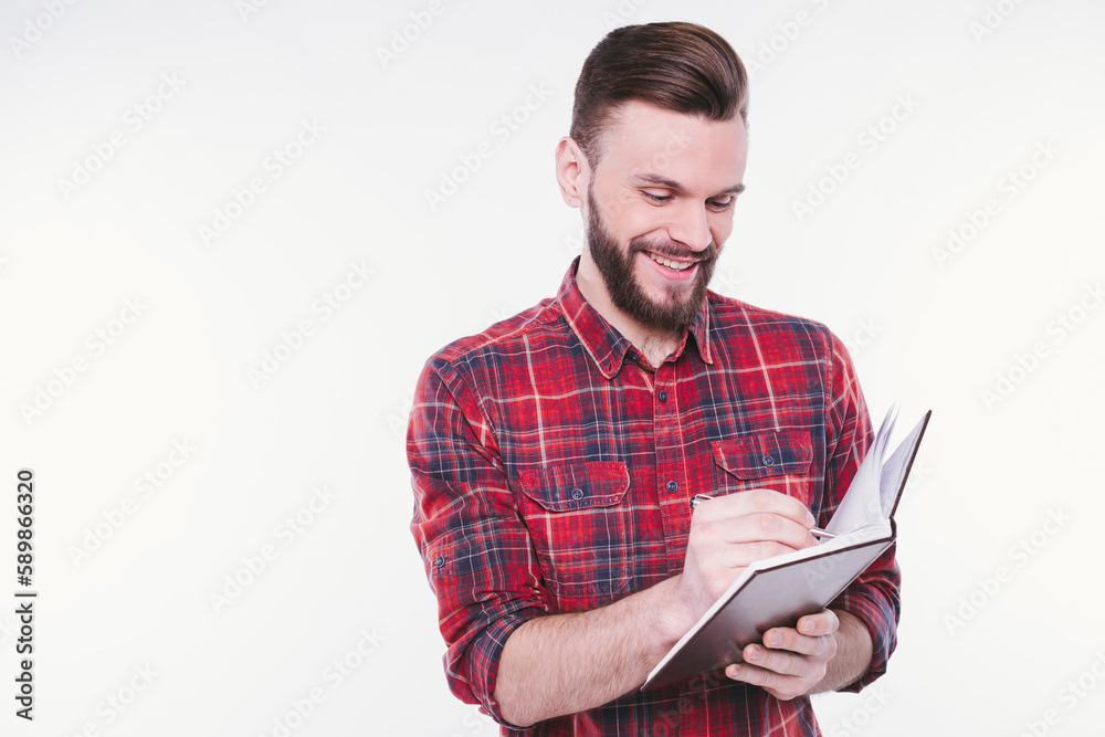 Portrait with copy space of thoughtful, serious, bearded man holding copybook and pen with success expression over white background. Study and teaching Portrait with copy space of thoughtful, serious, bearded man holding copybook and pen with success expression over white background. Study and teaching