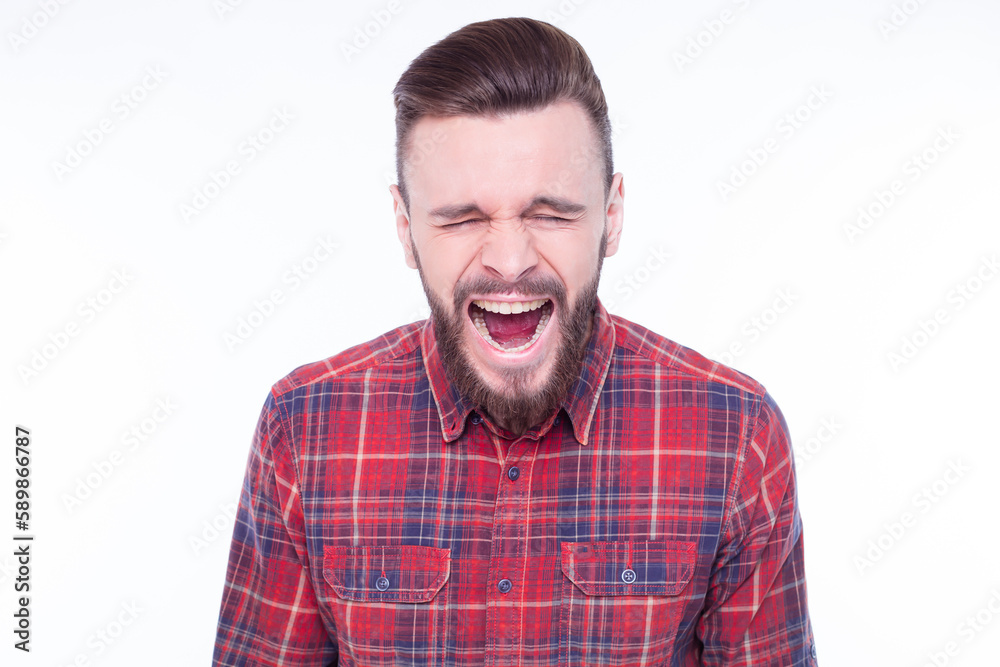 Young man wearing checkered shirt standing over isolated white background crazy and mad shouting and yelling with aggressive expression and arms raised. Frustration concept. Young man wearing checkered shirt standing over isolated white background crazy and mad shouting and yelling with aggressive expression and arms raised. Frustration concept.